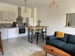 uma sala de estar com um sofá azul e uma cozinha em Le Jules Appart'Hotel em Romans-sur-Isère