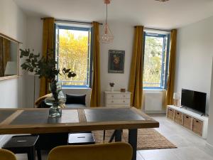 uma sala de estar com uma mesa e uma televisão em Le Jules Appart'Hotel em Romans-sur-Isère