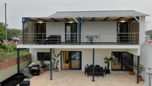 ein Haus mit einem Balkon mit Tischen und Stühlen in der Unterkunft Olivia Estate South Corfu in Bastátika