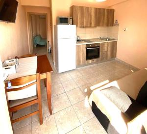 a kitchen with a table and a white refrigerator at Jasmin Apartment Blue in Hanioti