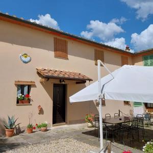 a house with a table and a white umbrella at Bed&Breakfast Pianeta Benessere in Pistoia