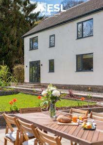 a table with a vase of flowers and a house at Large Country Farmhouse with Hot Tub and Shropshire Hills View in Minsterley