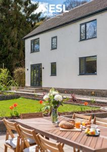 a table with a vase of flowers and a house at Large Country Farmhouse, Shropshire Hills View, with Hot Tub in Minsterley