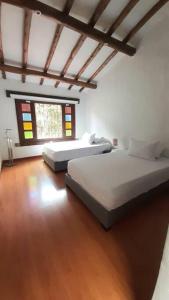 two beds in a room with a wooden floor at Spain style country house in Cajica in Cajicá