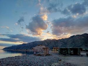 a beach with a hut and water and mountains at COSMOS eco Lodge and Spiritual community in Dahab
