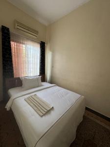 een slaapkamer met een wit bed en handdoeken bij G & S Executive Lodge in Dar es Salaam