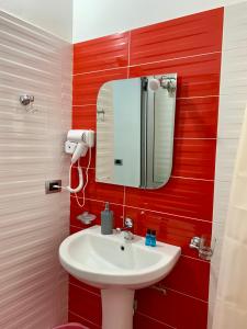 Hotel Piazza في سارنده: حمام مع حوض أبيض ومرآة