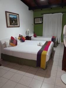 two beds in a room with green walls at HOTEL LOS ARCOS El placer de lo natural in Perico +14 photos