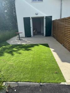 a yard with green grass in front of a building at Magnifique T2 neuf au centre de Cambo les bains in Cambo-les-Bains