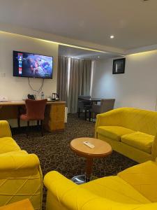 una sala de espera con muebles amarillos y TV de pantalla plana. en Hotel 5092 en Abuja