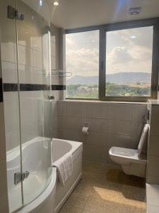 a bathroom with a tub and a toilet and a window at Hotel 5092 in Abuja