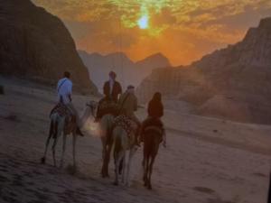 a painting of four people riding horses in the desert at Talal Wadi Rum in Wadi Rum