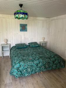 1 dormitorio con 1 cama con edredón verde en Gîte de la tuilerie des Garandons en Saint-Menoux