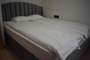 un letto con lenzuola bianche e 2 cuscini di Suur-Posti Apartments a Pärnu