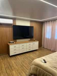 a bedroom with a flat screen tv on a dresser at Casa pertinho da praia com hidro in Rio das Ostras