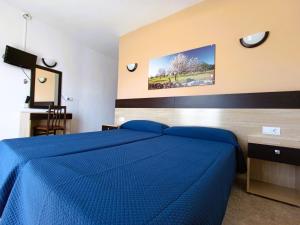 sypialnia z niebieskim łóżkiem w pokoju w obiekcie Hostal Horizonte w mieście San Antonio