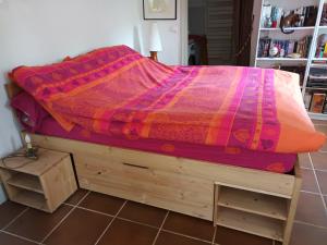 a bed with a colorful comforter on top of it at Annexe indépendante in Bourron-Marlotte