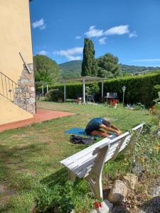 un hombre tendido en la hierba junto a un banco blanco en Agriturismo Il Gelso, en Pomaia
