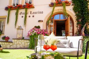 a patio with a couch and flowers in front of a building at Hotel Garnì Laurino in Cavalese