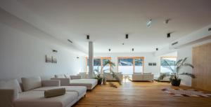 una gran sala de estar con muebles blancos y suelo de madera. en Weinhaus Nigl - Hotel, Restaurant und Spa en Senftenberg