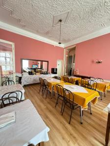 Habitación con mesas, sillas y paredes rosas. en Central Guest House, en Figueira da Foz