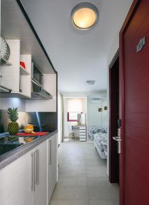 a kitchen with a red door and a room with beds at Elpiniki Luxury Rooms in Nea Potidaea