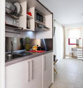 una cocina con armarios blancos y fregadero en Elpiniki Luxury Rooms, en Nea Potidaea