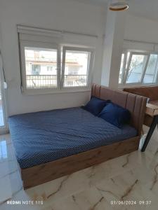 a bed with blue sheets in a room with windows at Zara's Boutique near Venizelos metro station in Thessaloniki