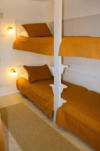 Casa Hotel Sahy في بارا دو ساهي: سريرين بطابقين في غرفة مع أوراق برتقالية
