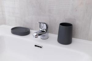 un lavandino in bagno con rubinetto e bidone della spazzatura di Villa Ninfa Alburnea ad Anzio Altre 21 foto