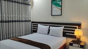 a bedroom with a bed and a table with a lamp at H. V Hotel Bandara Gorontalo in Bongomeon