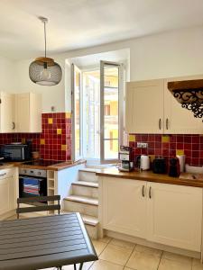 une cuisine avec des armoires blanches et une table à l'intérieur dans l'établissement Vacances bord de mer - Appartement Sanary sur Mer, à Sanary-sur-Mer