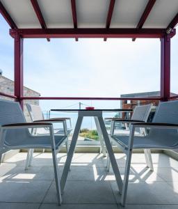 un tavolo in vetro e sedie sul balcone di Elpiniki Luxury Rooms a Nea Potidaea