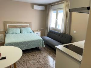 a bedroom with a bed and a couch and a table at Apartamentos Pelicano in Benidorm