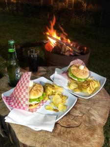 a table with two sandwiches and chips and a fire at Refugio Aventura, romántico glamping montañero in Tabio