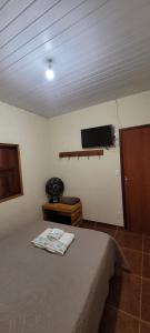 1 dormitorio con 1 cama y TV en la pared en CHALÉS MUCIOS, en Serra do Cipo