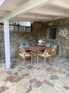 a table and chairs on a patio with a stone wall at Maison Du Reve Scario in Scario