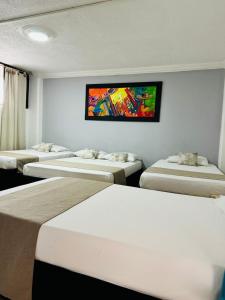 Habitación con 4 camas y TV en la pared. en Rey de Reyes, en Valledupar