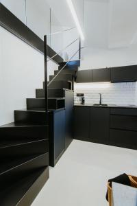 a staircase in a kitchen with black cabinets at La Casa del Conde - Un alojamiento único en Écija in Écija