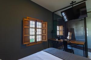 a bedroom with a bed and a desk and a window at La Casa del Conde - Un alojamiento único en Écija in Écija