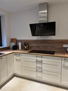 a kitchen with white cabinets and a stove top oven at Ferienhaus Zipfelstube in Selfkant