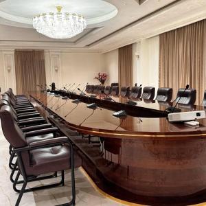 una gran sala de conferencias con una mesa larga y sillas en KANGURT Grand Hotel en Dushanbe