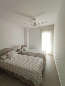 Dos camas en una habitación blanca con ventana. en Nasila Beach & Golf, en Motril