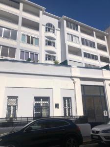 un edificio blanco con un coche aparcado delante de él en LOENA CANNES CENTRE - Appartement rénové 2 pièces - 4 personnes - proche croisette palais festival plage - internet gratuit - climatisation - non fumeur en Cannes