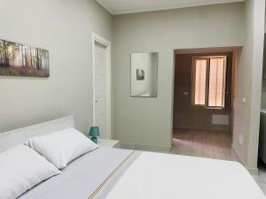 a white bedroom with a bed and a window at Horus Home in Torre del Greco