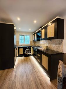 cocina grande con armarios negros y suelo de madera en Scandinavian Haus For 8 en Mánchester