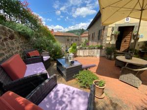 a patio with chairs and tables and an umbrella at La Magione dei Todaro in Borgo a Buggiano