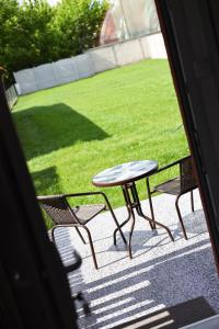 a table and chairs on a porch with a lawn at Harmonija in Palić