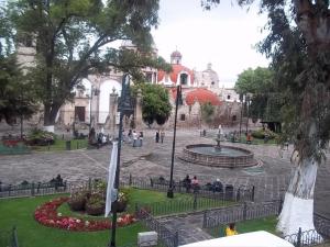 un parque con una fuente y gente sentada en la hierba en Hotel el Carmen en Morelia