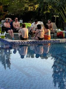 a group of people sitting around a swimming pool at The New Njiro Legacy in Arusha